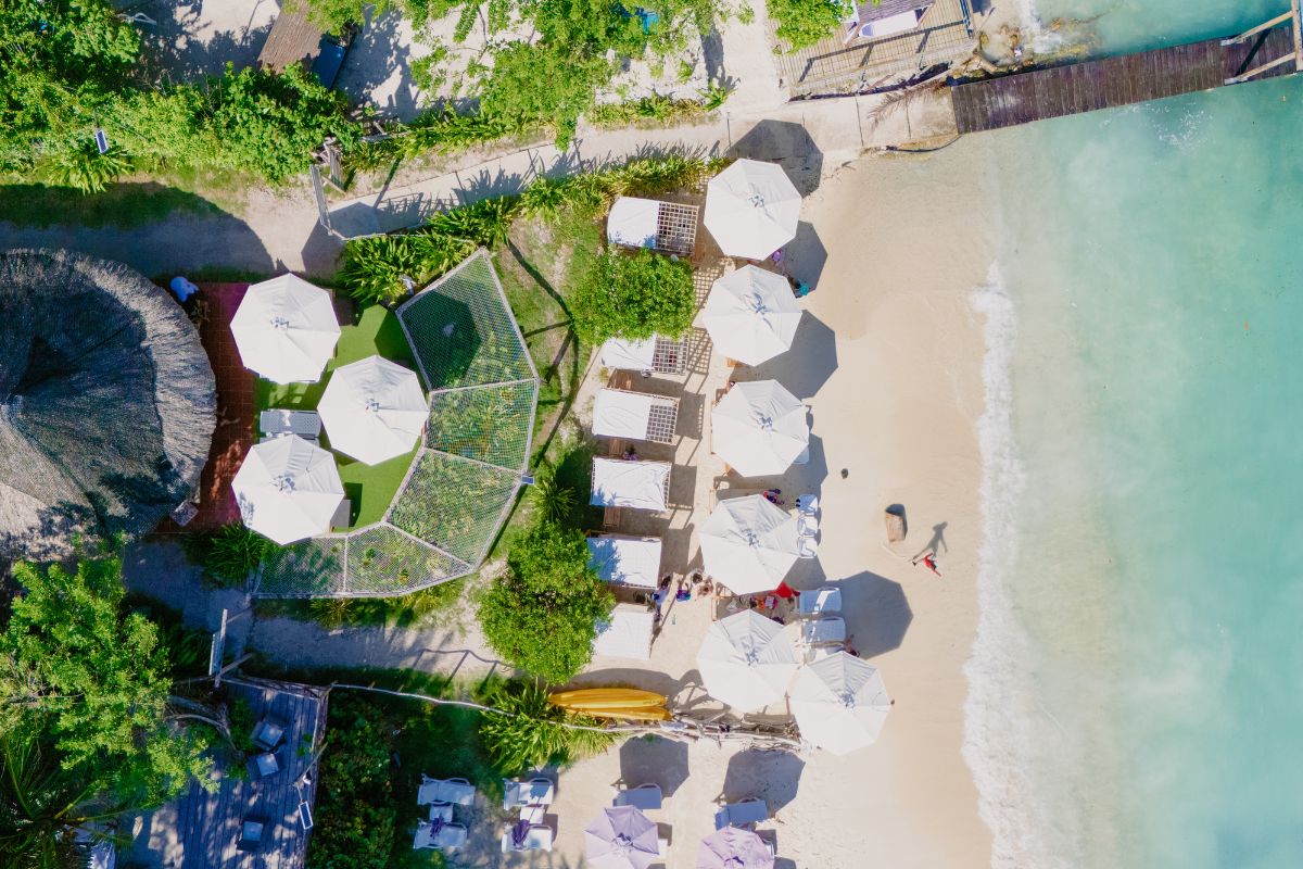 Vista aérea Playa Rosario Beach con camas de playa, sombrillas blancas y aguas turquesas en Islas del Rosario.